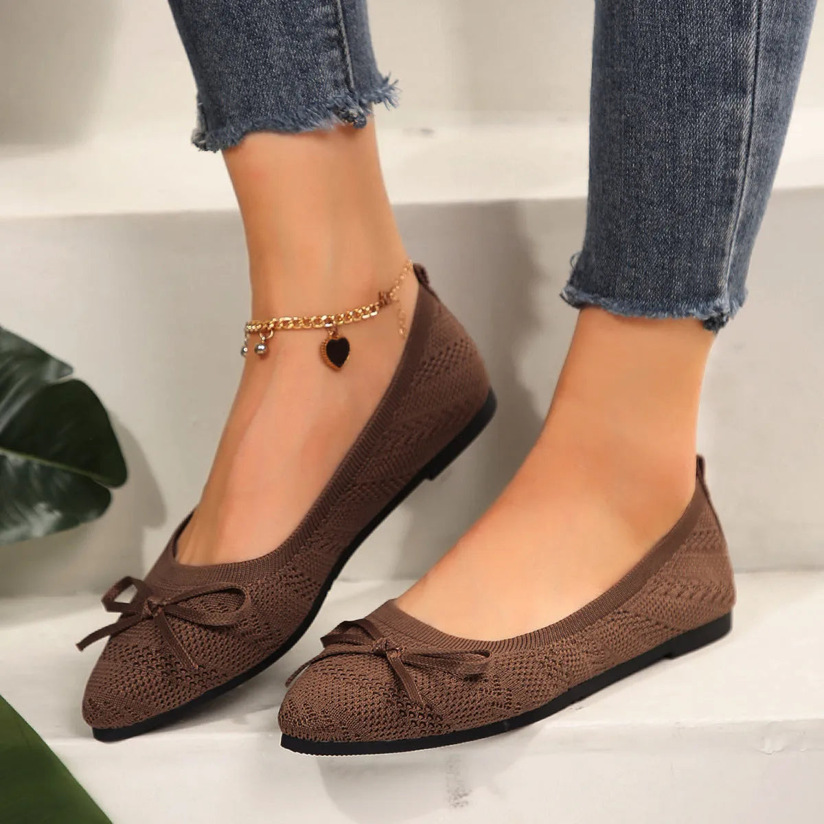 Women's knitted loafers with bow decoration in various colours showing flat rubber soles