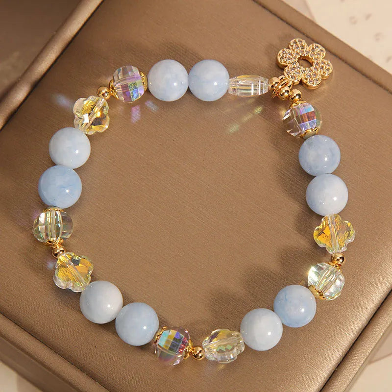 Women's aquamarine crystal bracelet with four-leaf clover charm and pearl accent on a chain