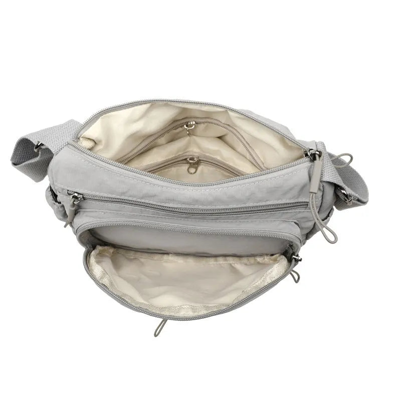 Water-repellent nylon crossbody cloth bag showing internal zipper compartments and shoulder strap