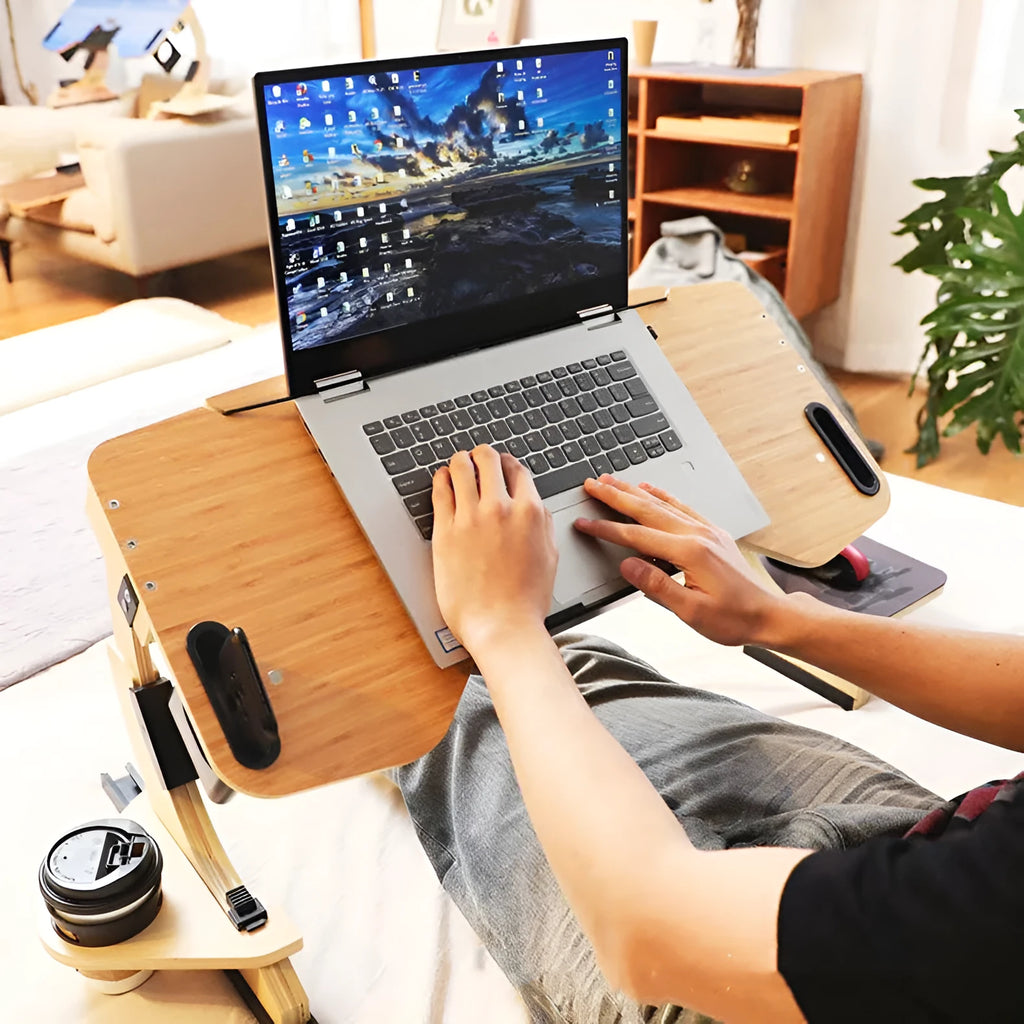 White wooden folding computer desk with adjustable angle, shown on a bed.