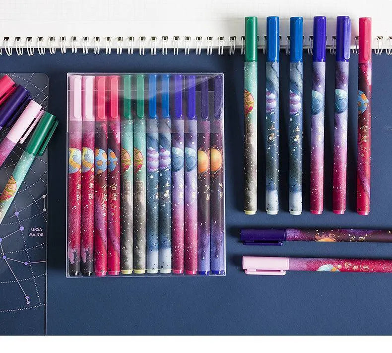 Twelve constellation ballpoint pens with zodiac designs on a light background