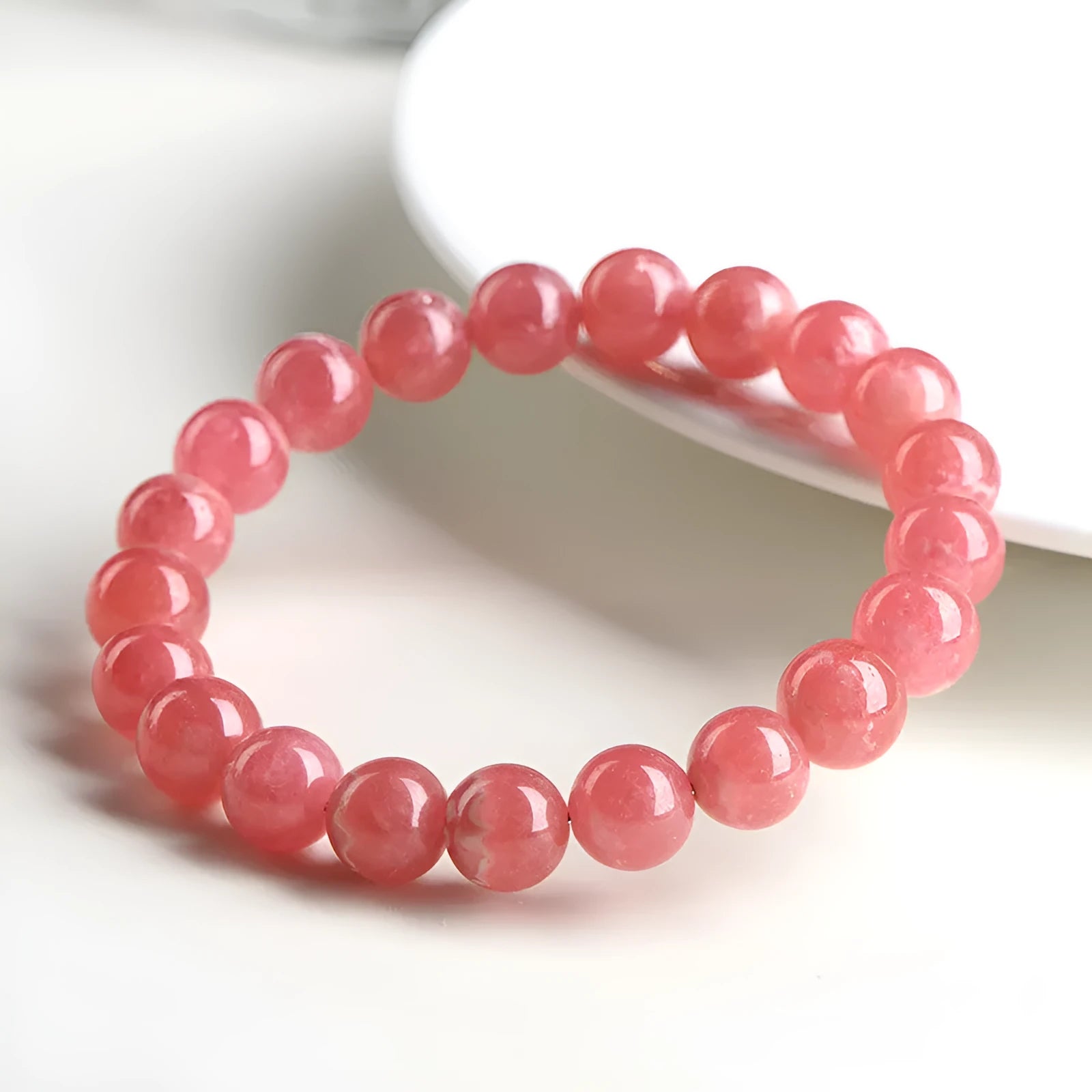 Women's geometric Rhodochrosite crystal bracelet with Longevity Lock feature on a wrist, showing red patterned stone beads.