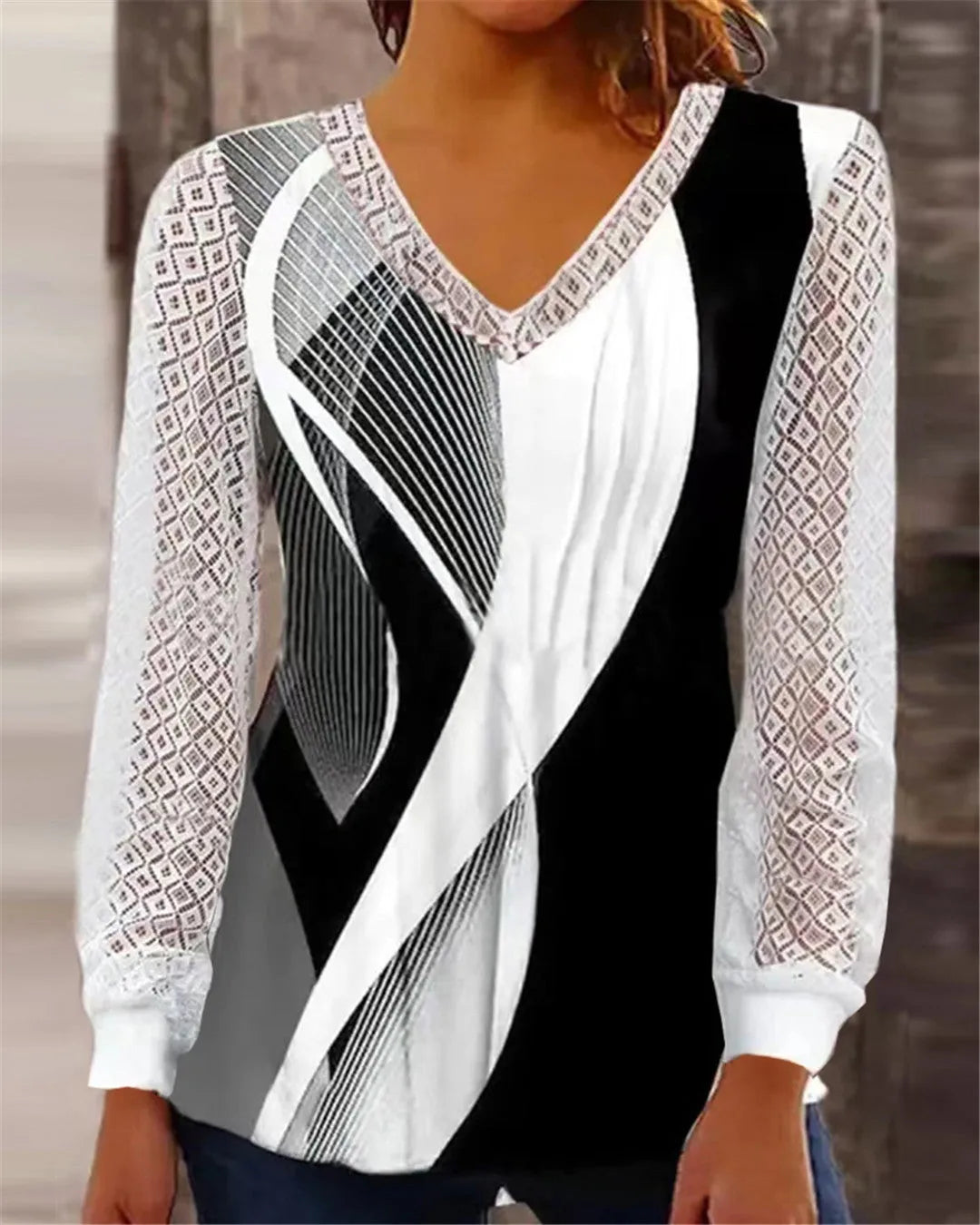 Purple loose V-neck top with lace print detail and long sleeves on a hanger.