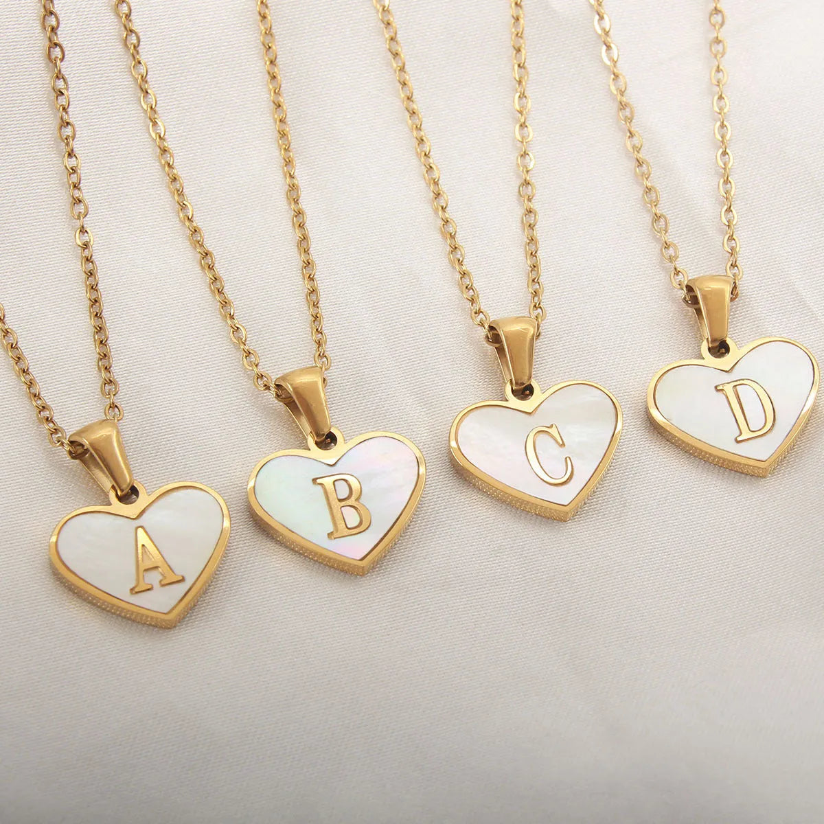Gold-plated heart necklace with white shell pendant and initial personalisation on a stainless steel chain.