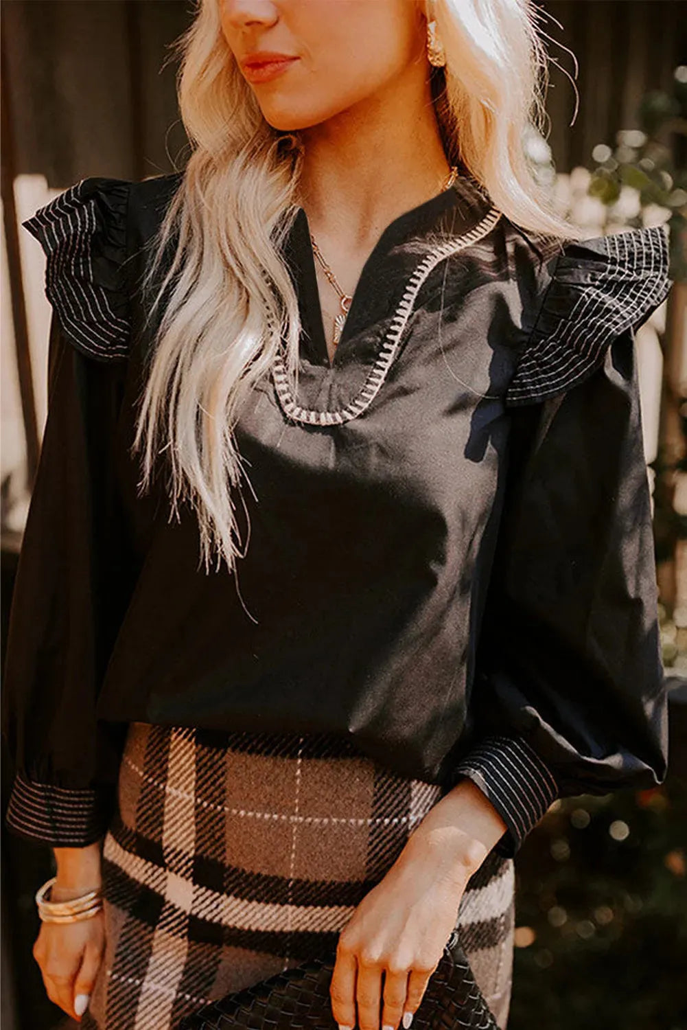 Black V-neck blouse with contrast stitching and ruffle long sleeves