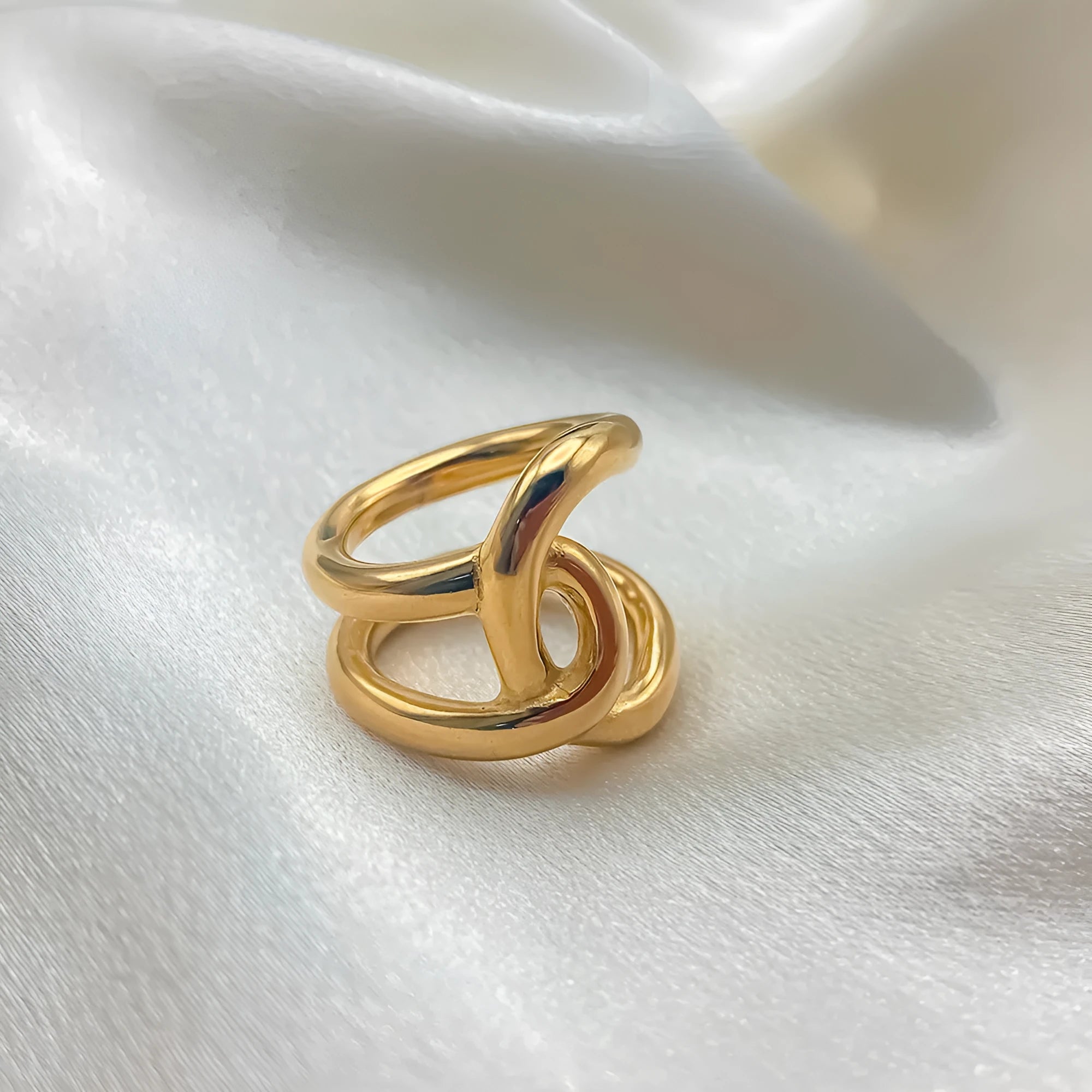 Women's stainless steel adjustable ring with knotted detail in gold or steel colour on a grey background.