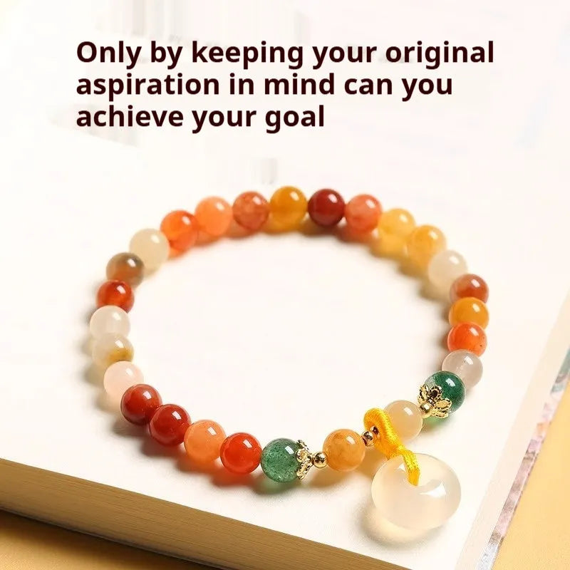 Handmade natural jade and red agate bracelet with silver safety buckle on wooden background