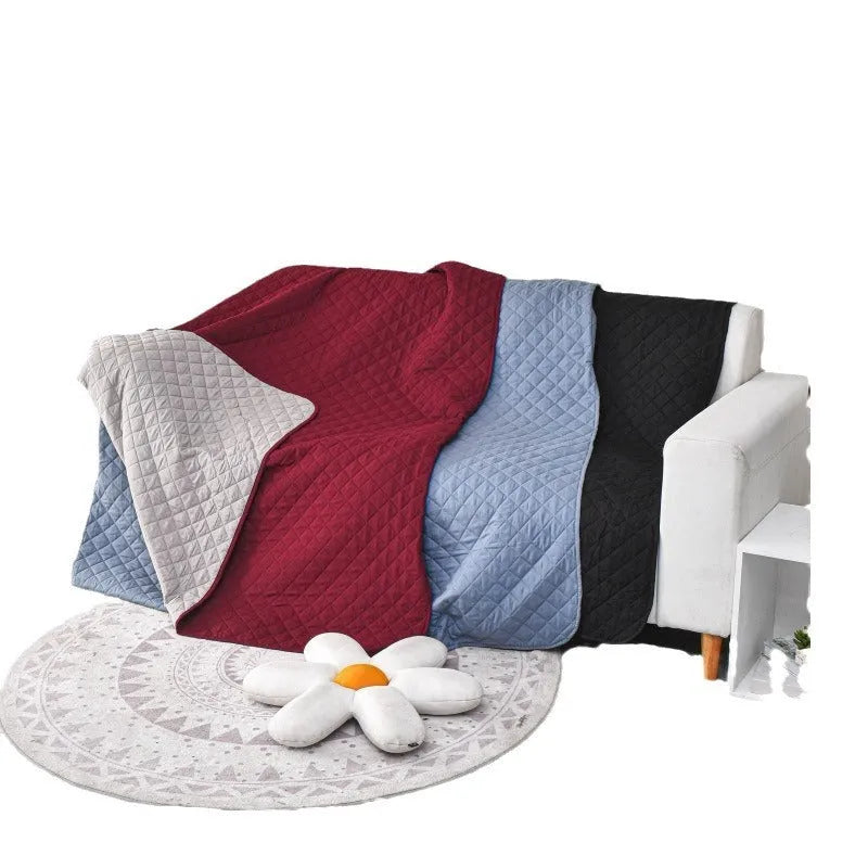 Reversible dog blanket on a sofa, showing two colour options, protecting furniture from pets.