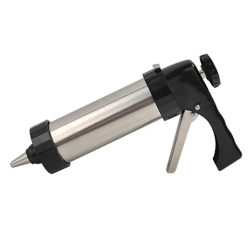 Stainless steel biscuit press gun with assorted cookie moulds and icing nozzles on a baking sheet.