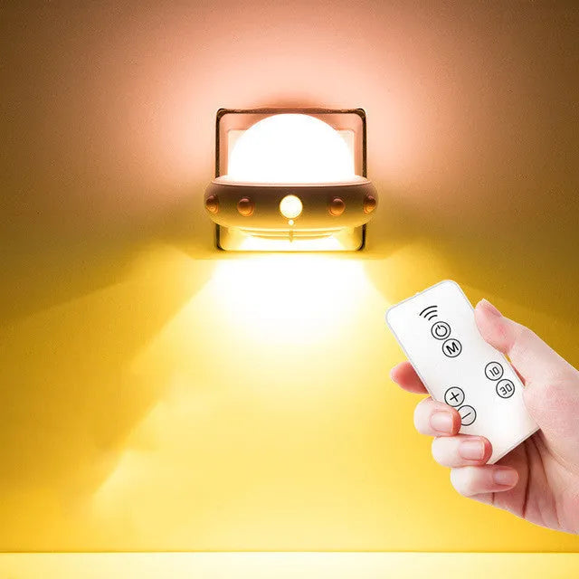 Remote control UFO shaped bedside night light in blue, pink or white colours on a table