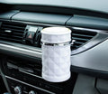 Black car ashtray made of ABS plastic hanging from a car air outlet vent.