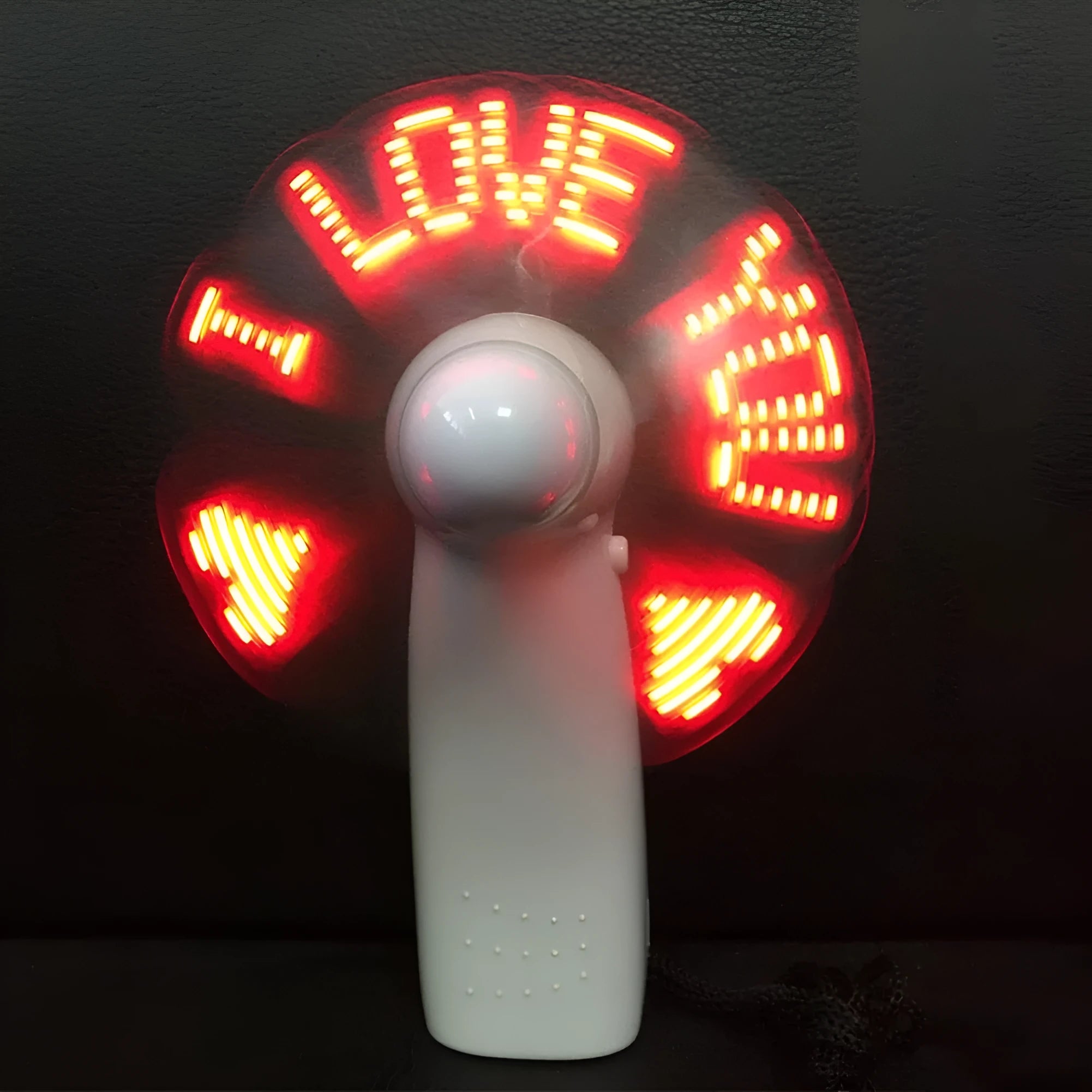 White handheld mini fan with blue and red LED love pattern display, shown next to AAA batteries for scale.