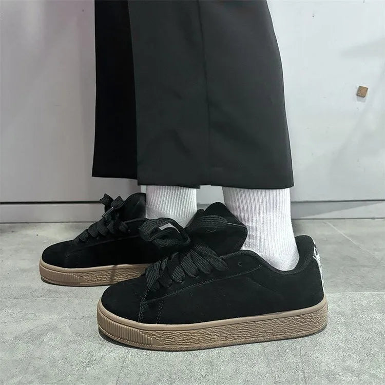 Black retro low-top sneakers with a platform sole and front lace-up closure on a white background.