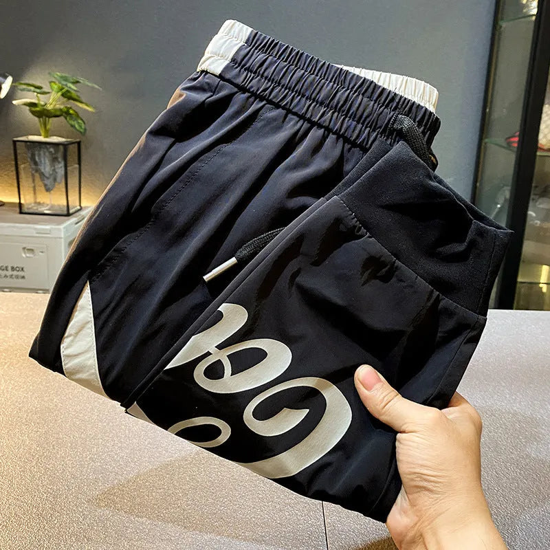 Black men's casual cotton trousers with cropped legs and an ankle band on a solid background.