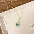 Women's pendant necklace with coloured glaze charm on a cotton and linen clavicle chain in Small Fish Lucky Bag colour.