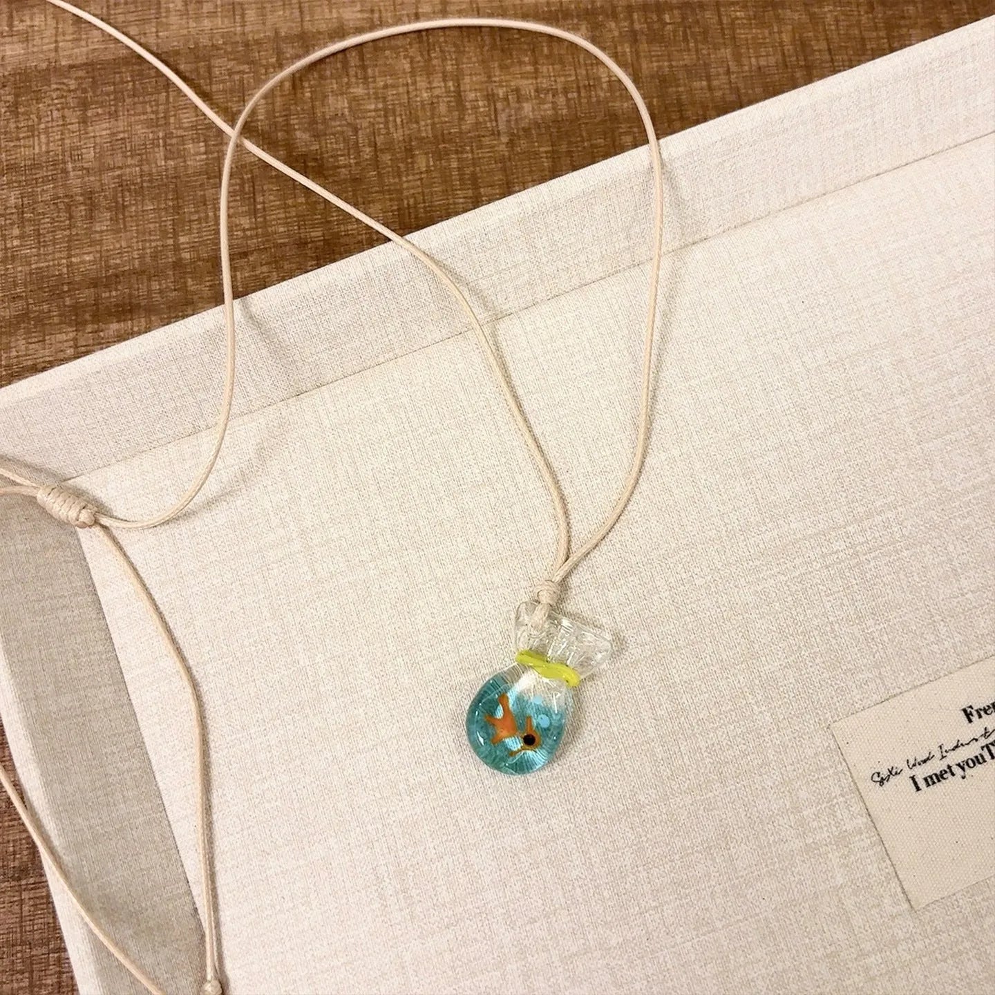 Women's pendant necklace with coloured glaze charm on a cotton and linen clavicle chain in Small Fish Lucky Bag colour.