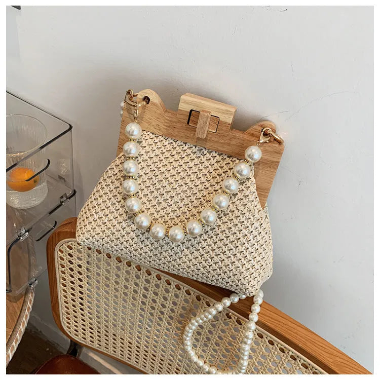 Women's straw woven shoulder bag with pearl chain strap and multiple internal compartments in horizontal square shape