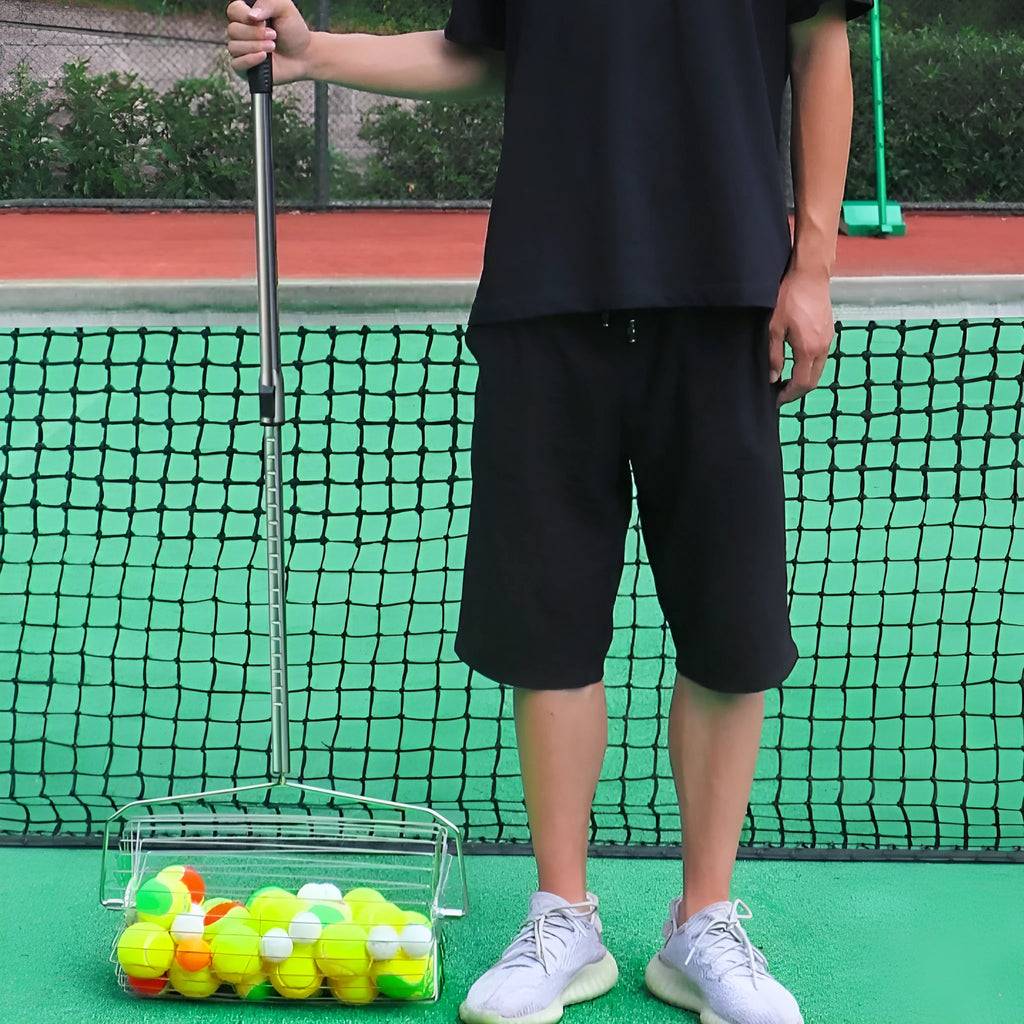 Stainless steel tennis ball picker with adjustable handle on a court.