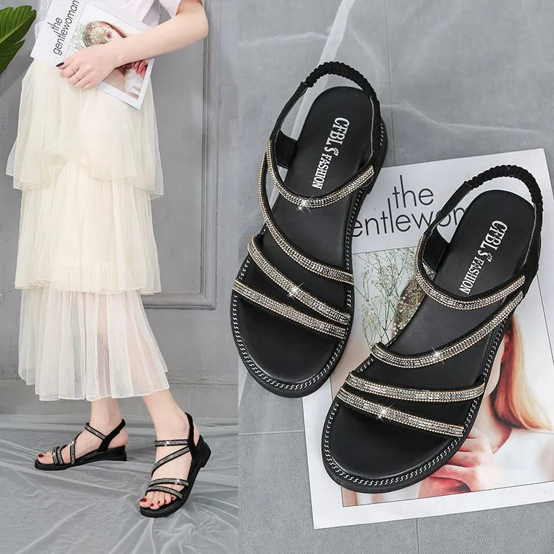 Women's flat casual sandals in gold with rhinestone details and an elastic band.