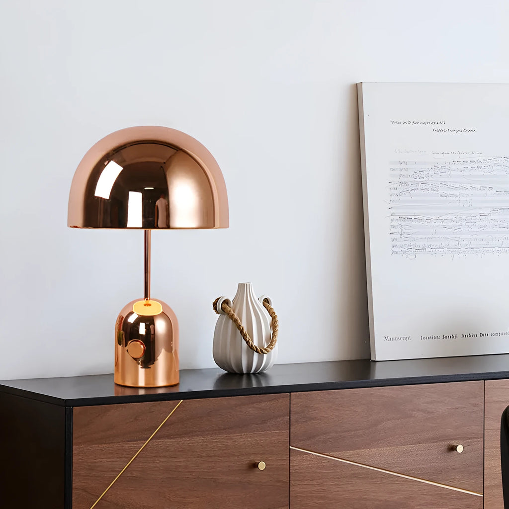 Mushroom-shaped table lamp with a metal base in rose gold finish on a wooden table.