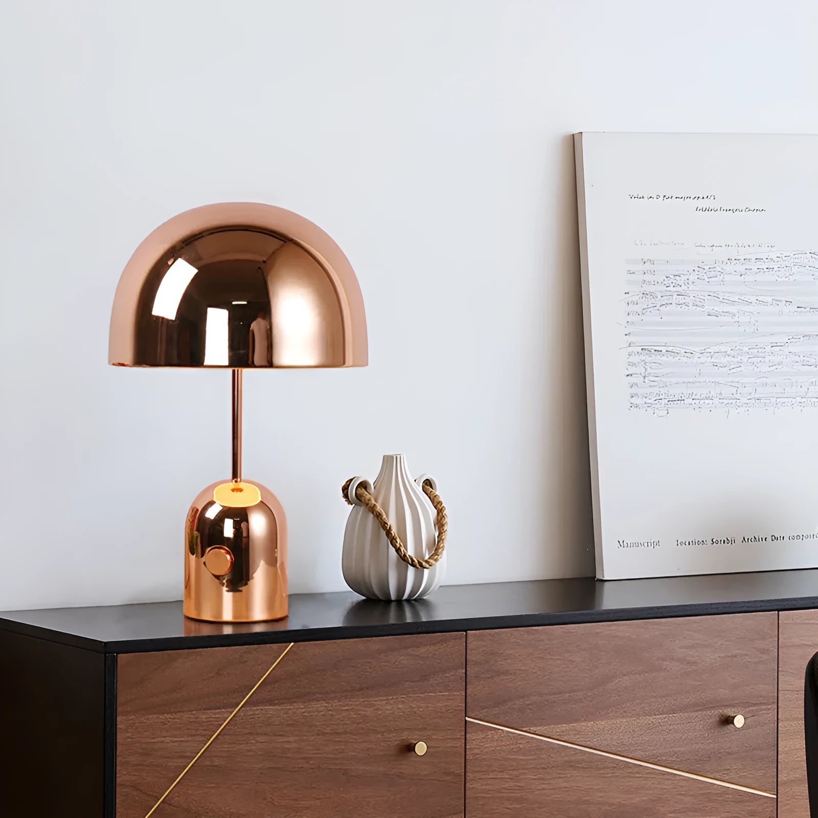 Mushroom-shaped table lamp with a metal base in rose gold finish on a wooden table.