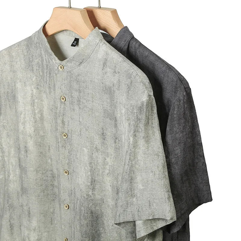 Man wearing a loose grey short sleeve cardigan shirt with a stand collar.