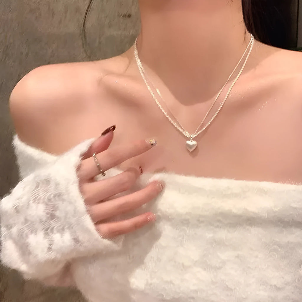 Double-layer brushed heart pendant necklace on model showing adjustable chain length