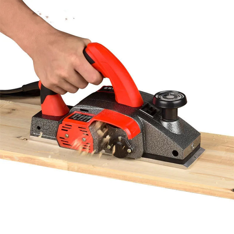 Red desktop electric wood planer with aluminium body, showing 82mm planing width