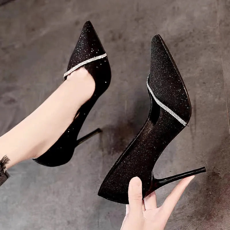 Gold and black women's pointed toe stiletto high heels on a plain background.