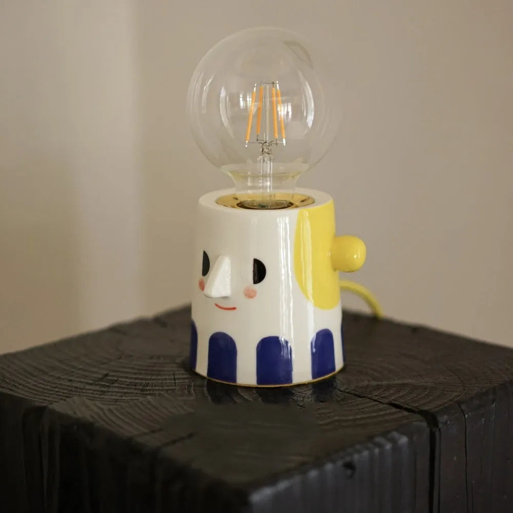 Handmade ceramic lamp with ball headlight design on wooden surface