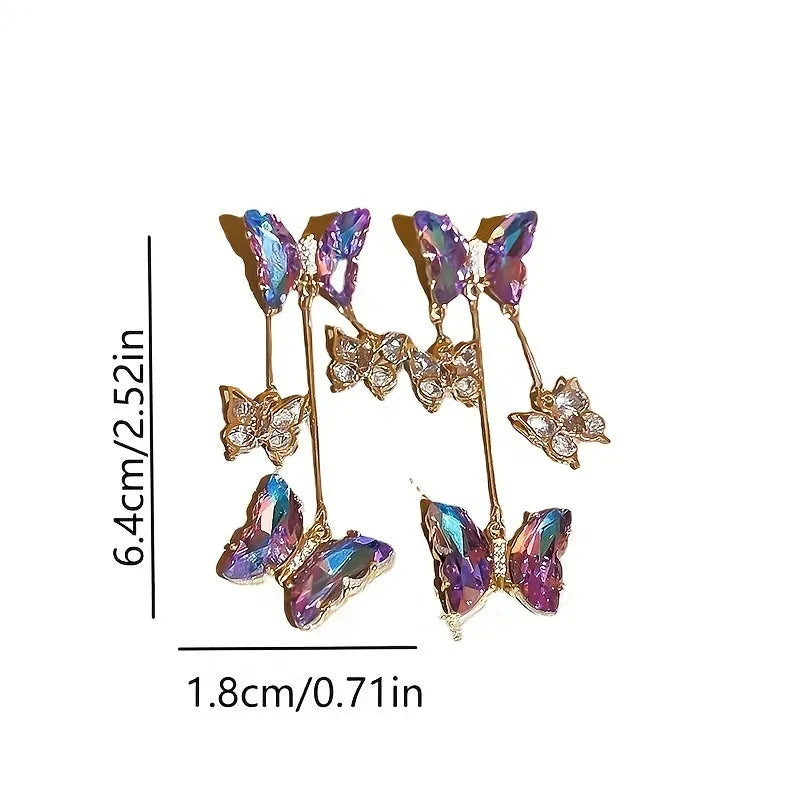 Women's silver needle coloured drop earrings with purple butterfly charm, crystal flowers, and tassels.