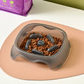 Blue plastic dog slow feeder bowl on a floor, designed to prevent choking by slowing eating pace.