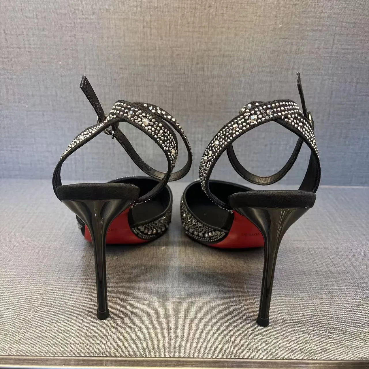 Women's black hollow high heel with stiletto heel, pointed toe, and red sole on a light background.