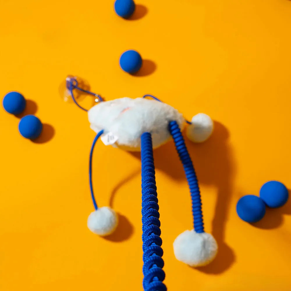 Blue plush cat toy with a telescopic elastic rope and a mint-coloured bell ring on a white surface.