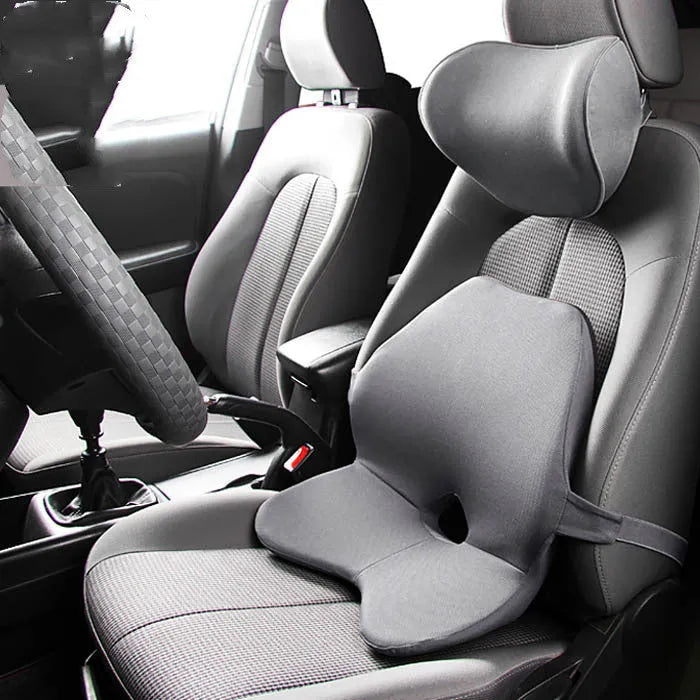 Black memory foam car lumbar support cushion with elastic straps, shown on a grey car seat.