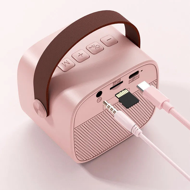 Compact white, pink, or blue plastic portable Bluetooth speaker with microphone on a surface.
