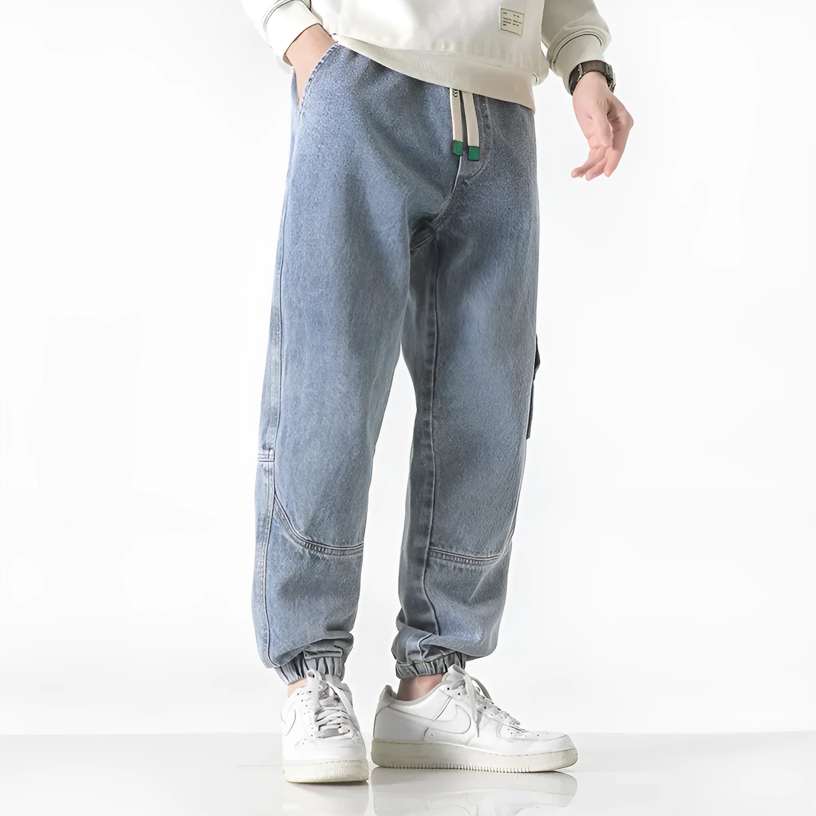 Men's loose-fit tapered cotton trousers in grey shown on a hanger.