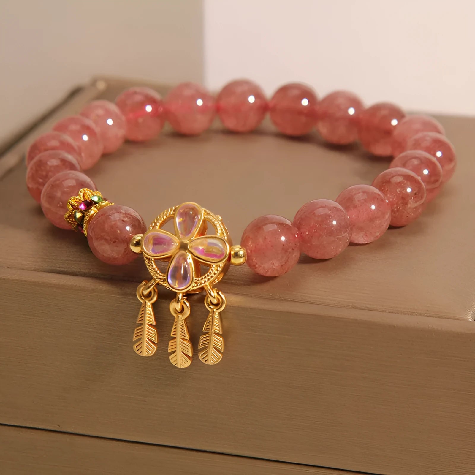 Natural strawberry quartz bracelet for women with a four-leaf dream catcher ball pendant on an elastic cord.