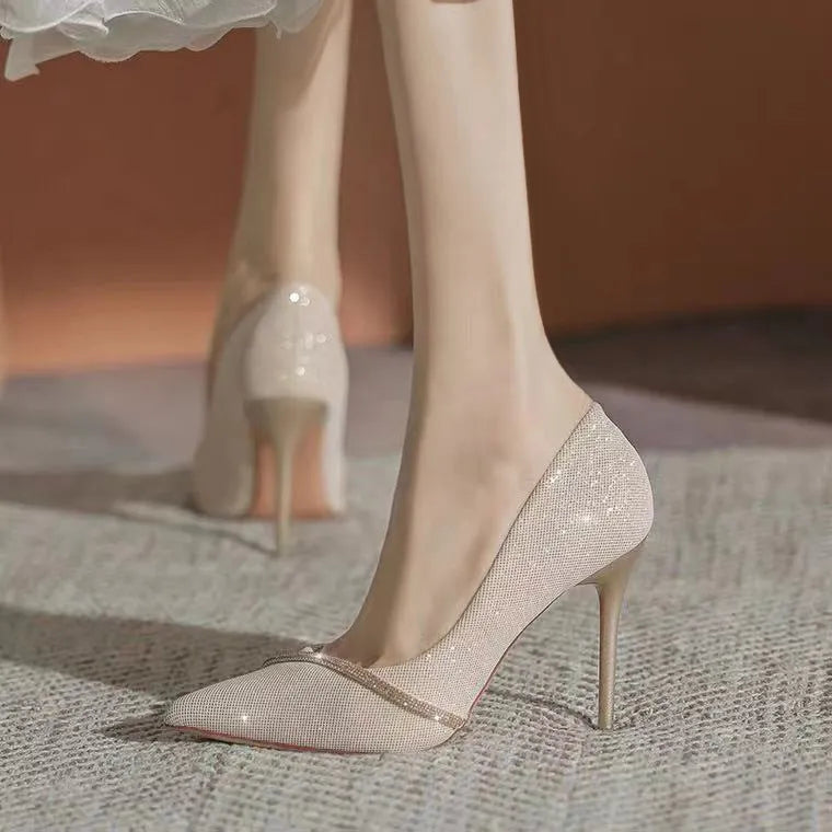 Gold and black women's pointed toe stiletto high heels on a plain background.