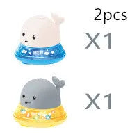 Automatic electric whale bath toy spraying water with LED lights on, floating in a baby bath.