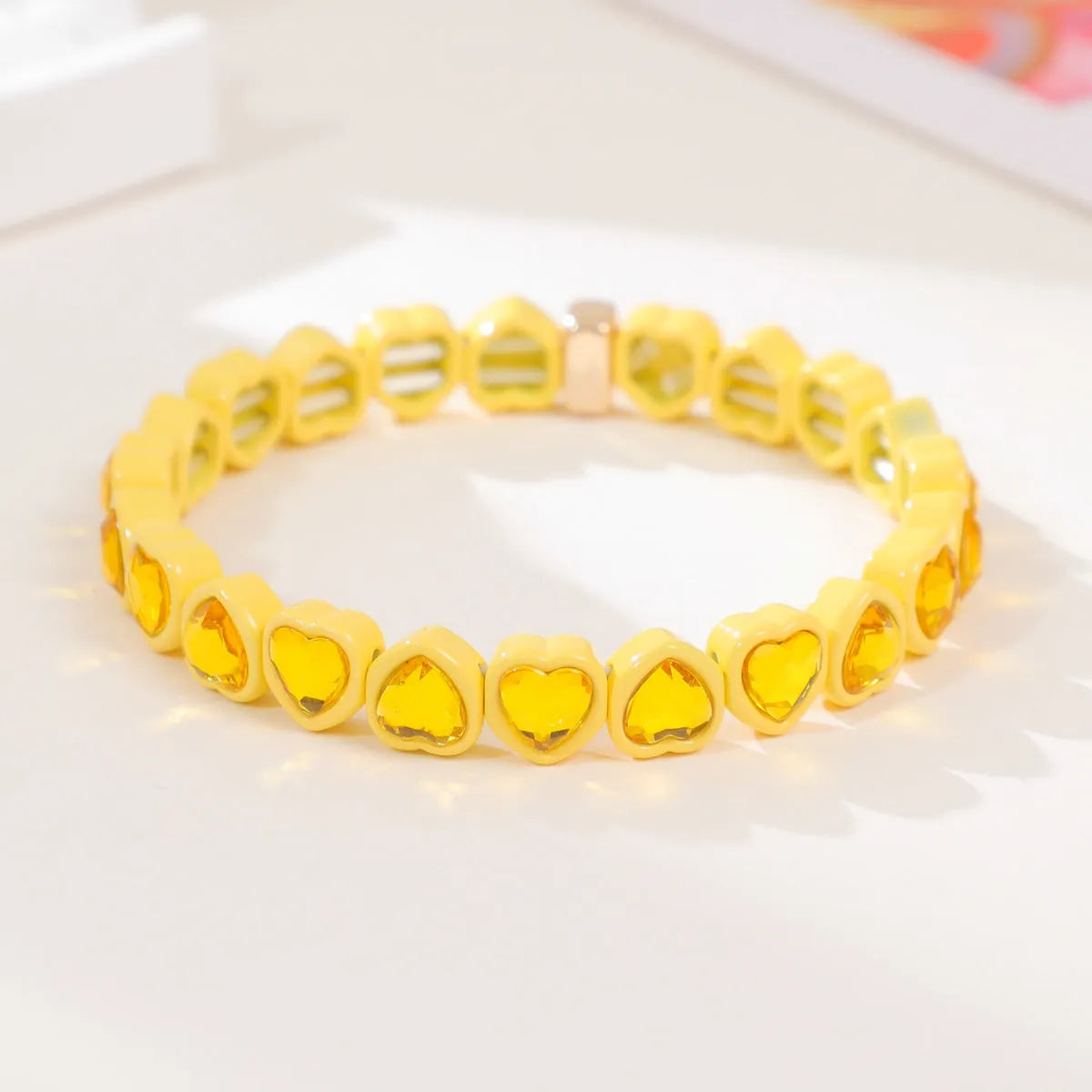 Colourful enamel finish alloy heart charm on a black stretch bracelet band.