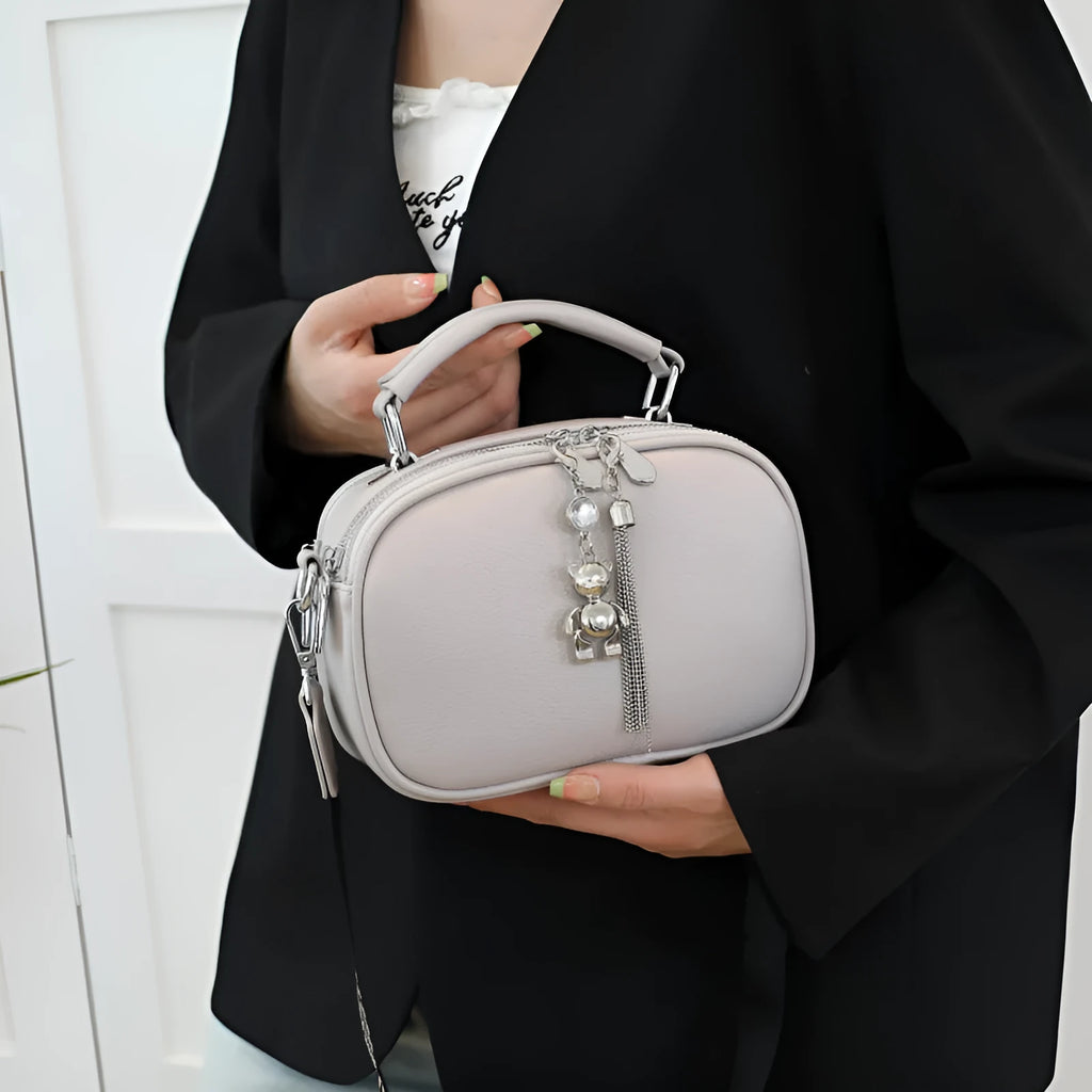 Women's small oval crossbody bag in PU with stitching detail and double straps, shown in multiple colours.
