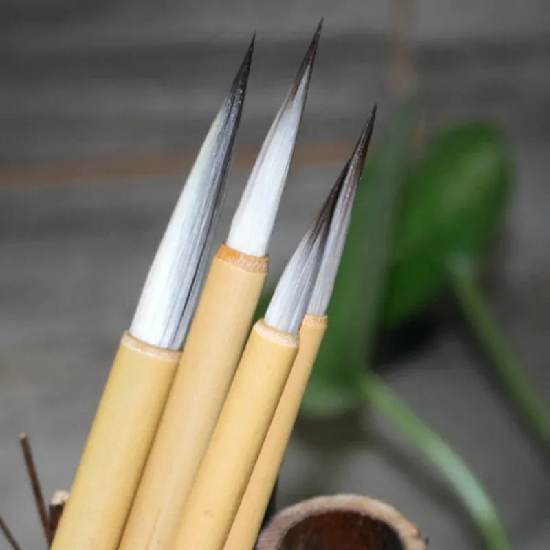 Set of four gold-handled writing brushes with mixed hair bristles for calligraphy.