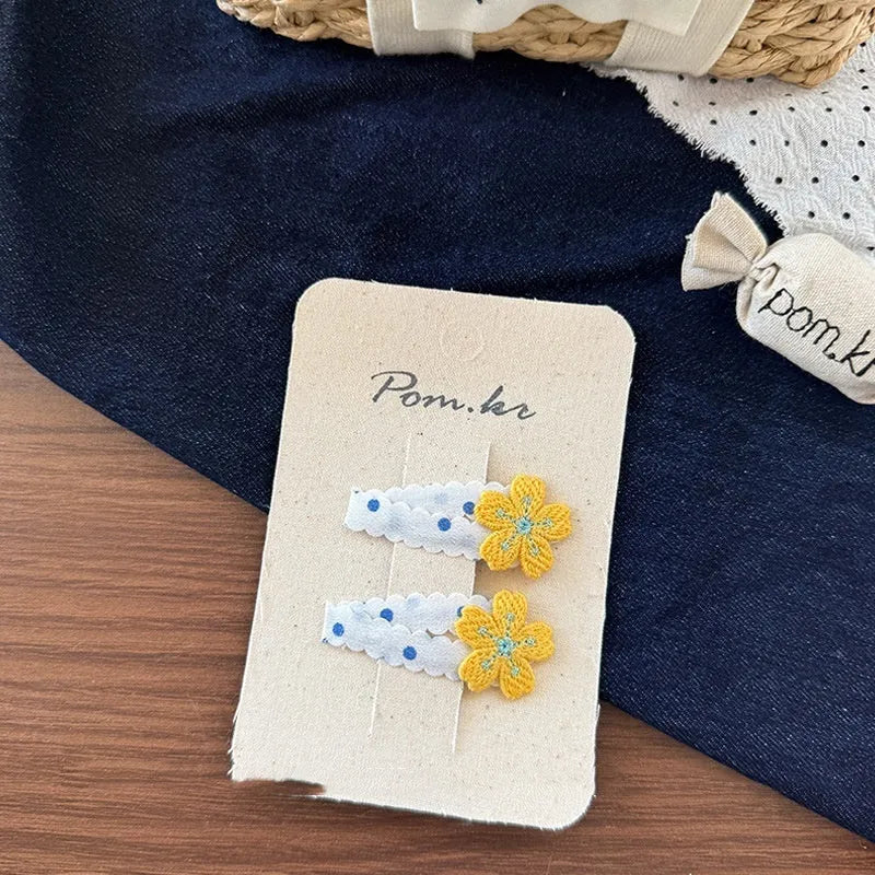 Children's denim handmade flower polka dot bow barrettes with triangle and duckbill clips on a light background
