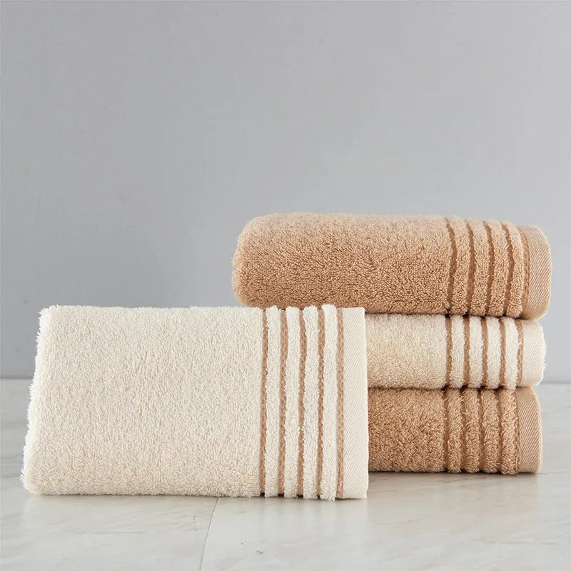Beige and brown cotton towel set showing three sizes: square face cloth, hand towel, and bath towel.