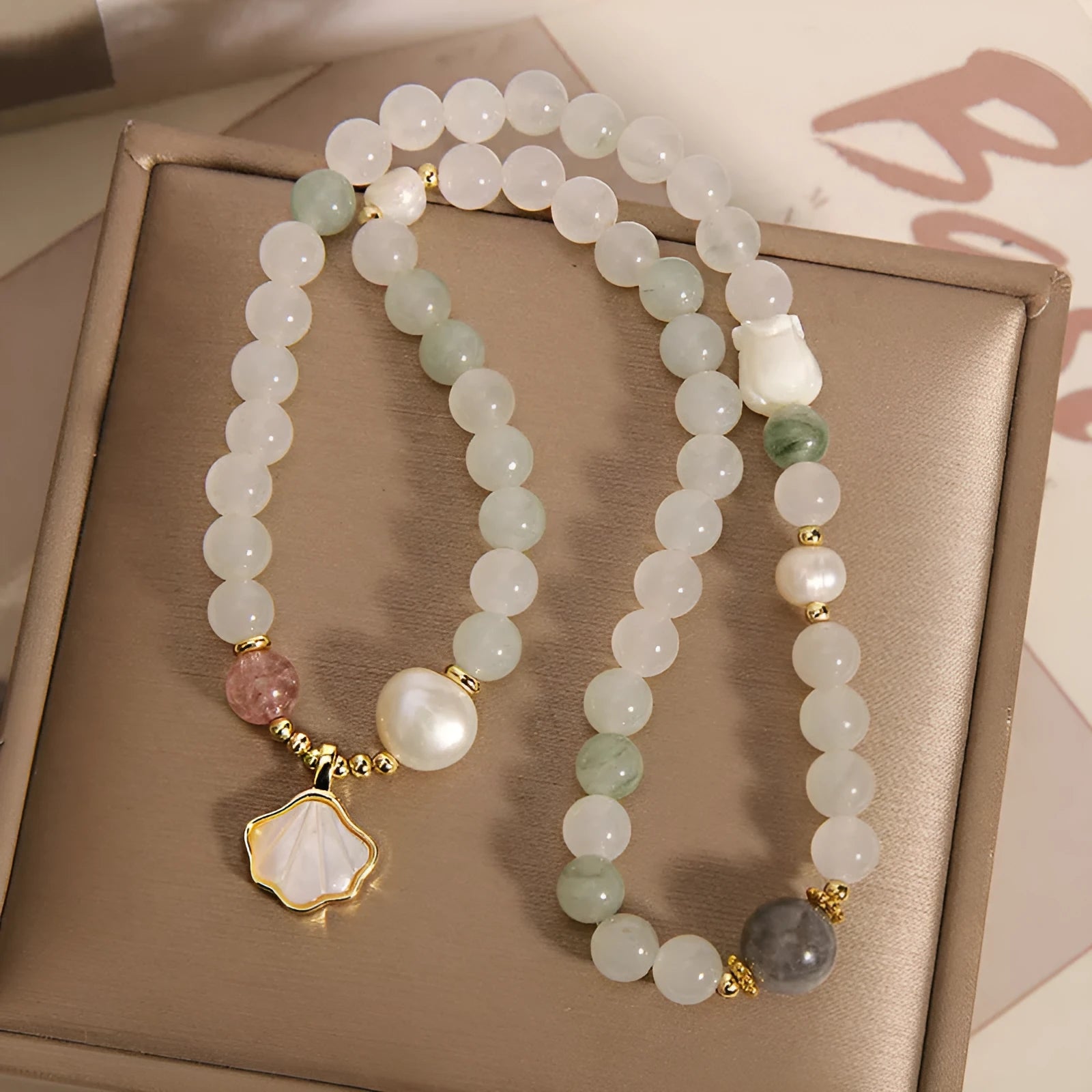 Women's crystal bracelet with gold ginkgo leaf pendant and rhinestones on a white background.