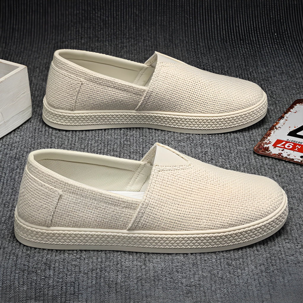 Men's beige canvas slip-on shoes with round toe and PVC sole on a plain background