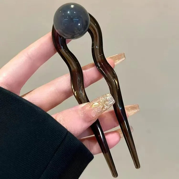 Acrylic U-shaped hair barrette with a small spherical decoration in a beige and caramel two-tone colour combination.