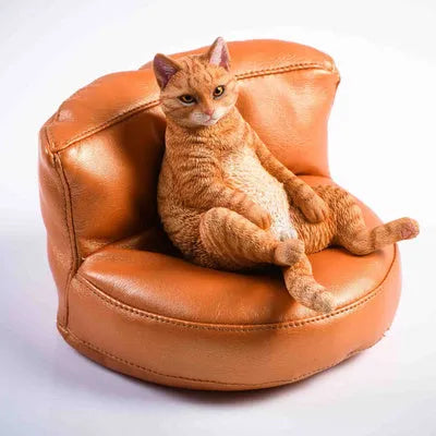 Small lazy cat figurine on a sofa, a 7.5cm high resin car dashboard ornament.