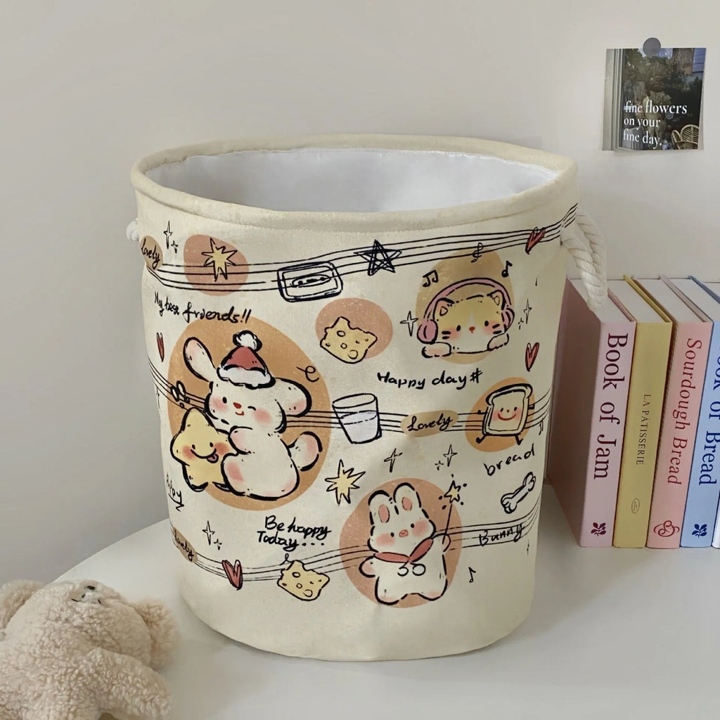 Foldable cotton laundry basket featuring an illustrated design, shown in a bedroom setting.